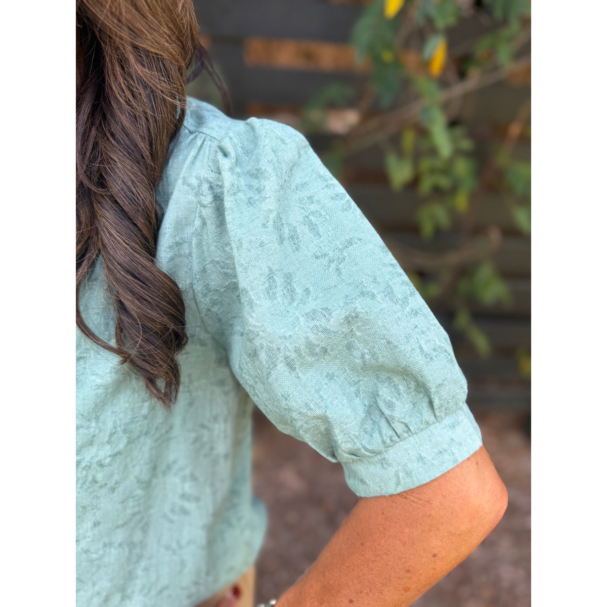 Annie Ks Boutique sage green textured cotton-linen blouse with puff sleeves, showing close-up of shoulder detail.