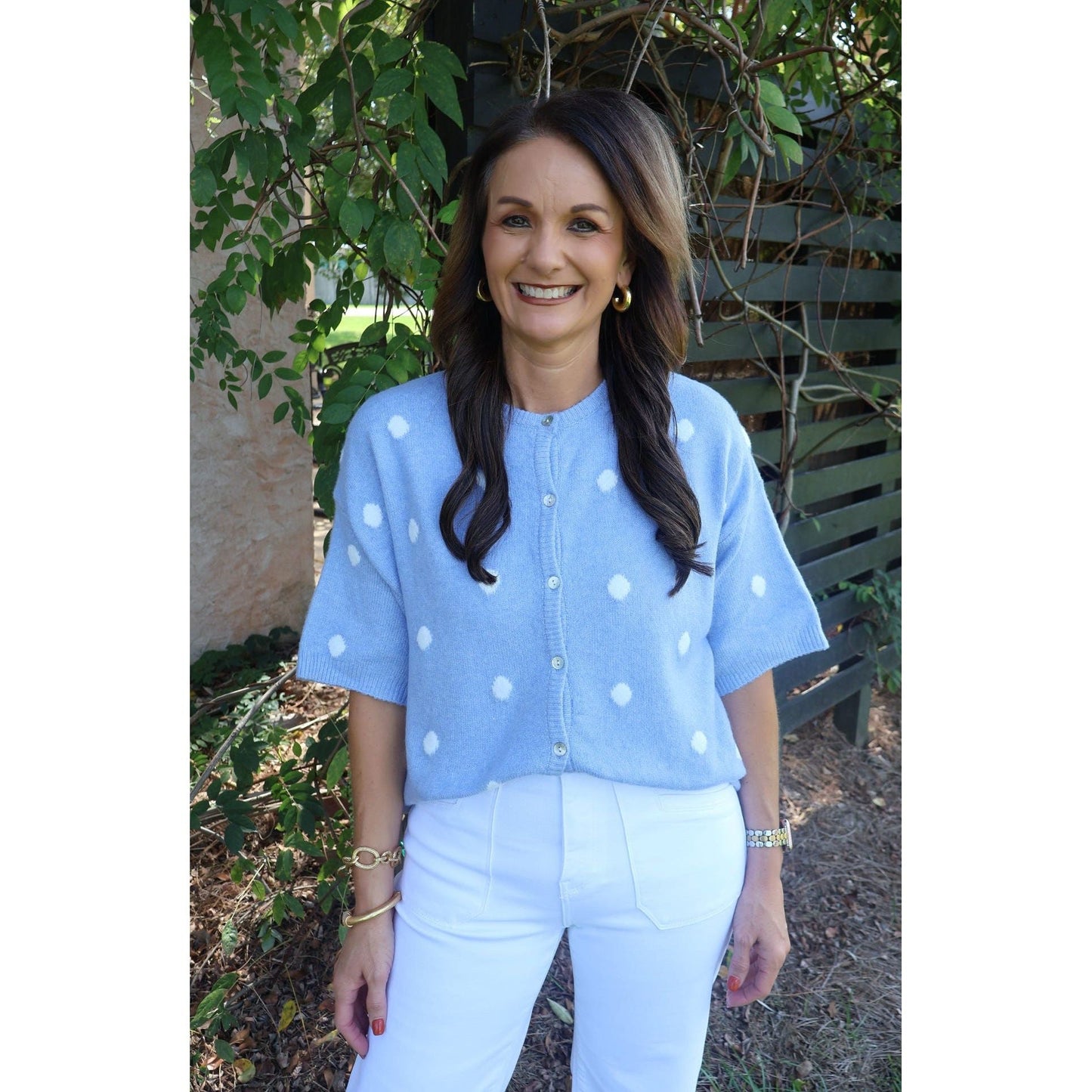 Annie Ks Boutique sky blue short-sleeve knit cardigan with white polka dots worn by a smiling woman outdoors
