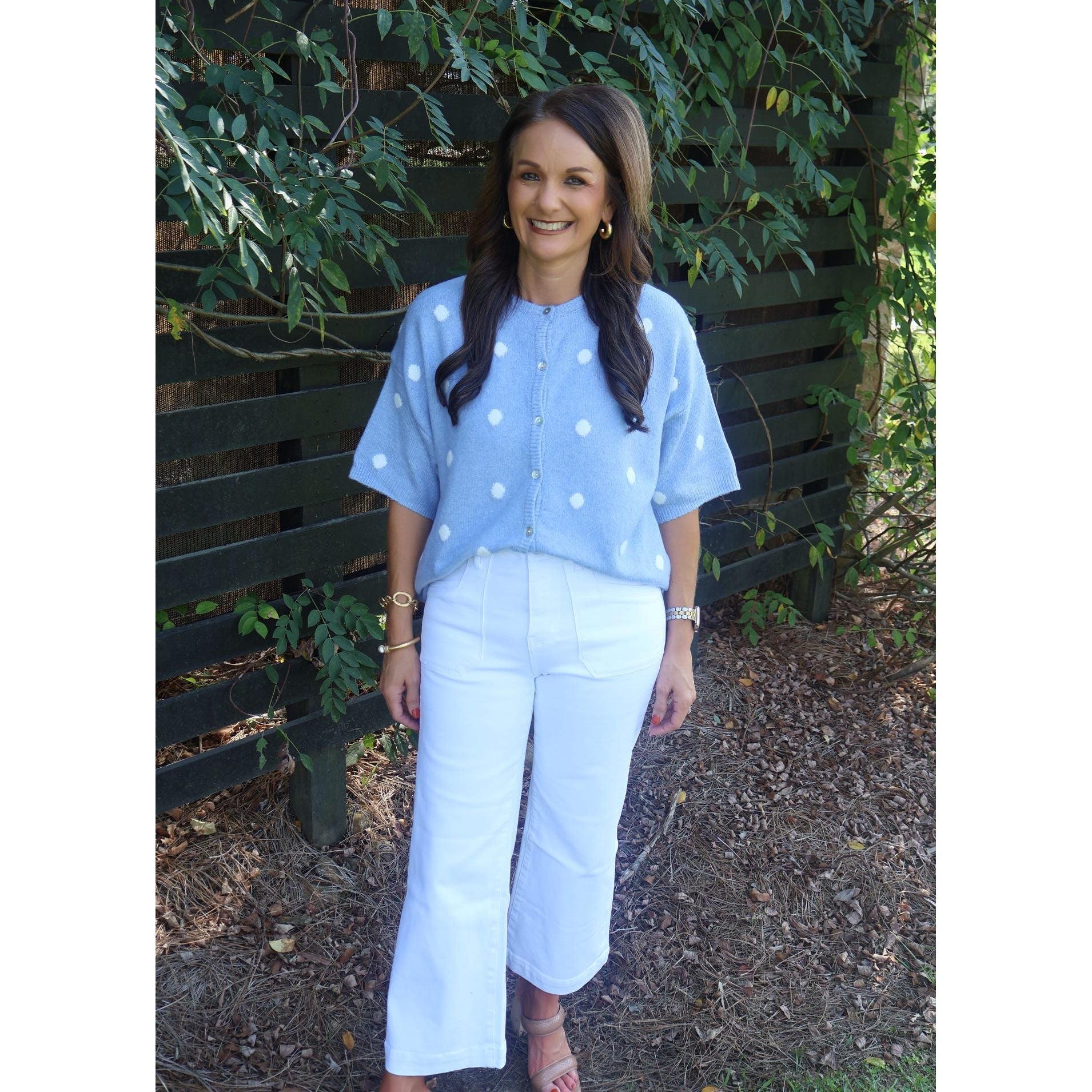 Annie Ks Boutique sky blue knit cardigan with white polka dots, crew neck, and short sleeves worn with white pants.