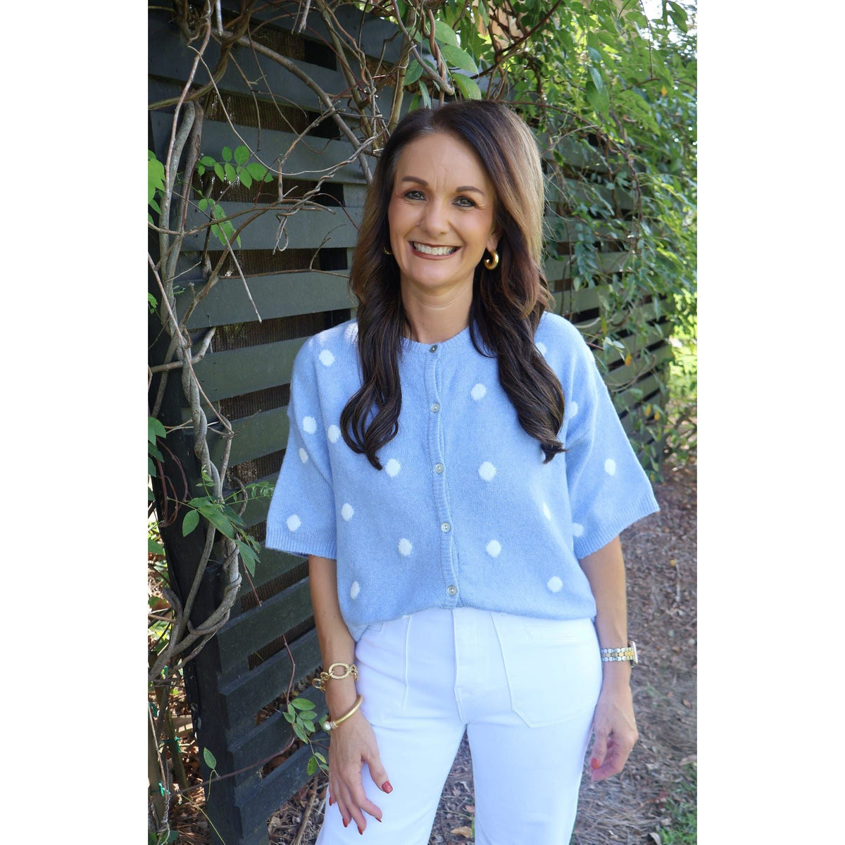 Annie Ks Boutique sky blue short-sleeve knit cardigan with white polka dots worn by a smiling woman outdoors