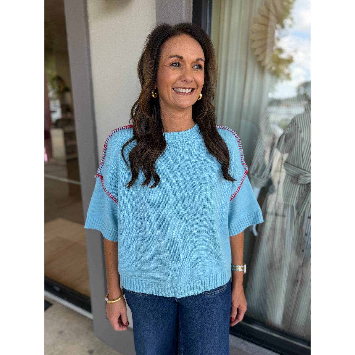 Annie Ks Boutique sky blue short sleeve sweater with red blanket stitch detail worn by a smiling woman