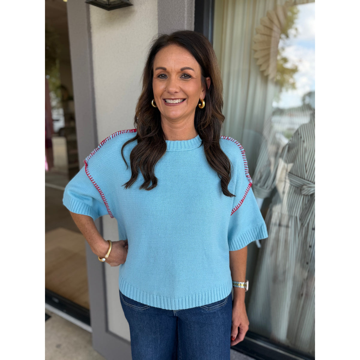 Annie Ks Boutique sky blue short sleeve sweater with red blanket stitch detail worn by a smiling woman