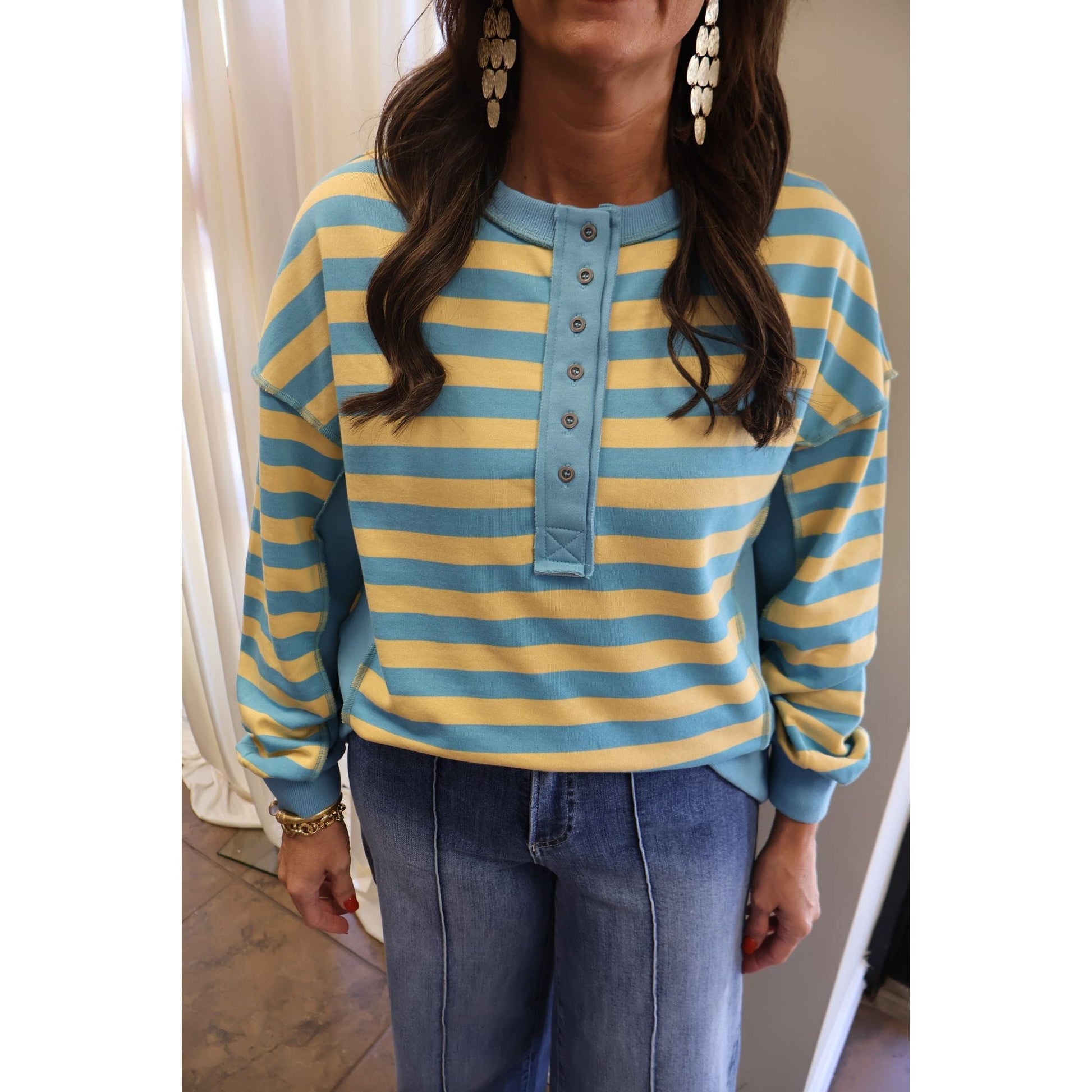 Annie Ks Boutique oversized yellow and blue striped knit top with half-button front and raw-edge sleeve details.