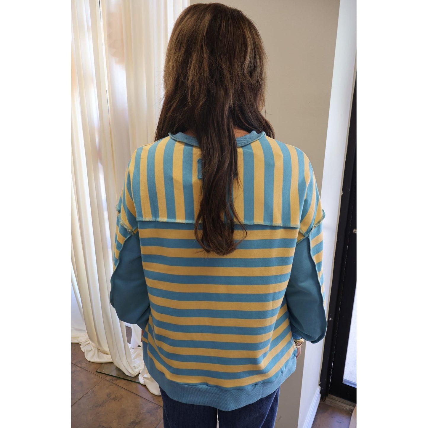 Back view of Annie Ks Boutique oversized yellow and blue striped knit top with drop shoulders and raw-edge seams