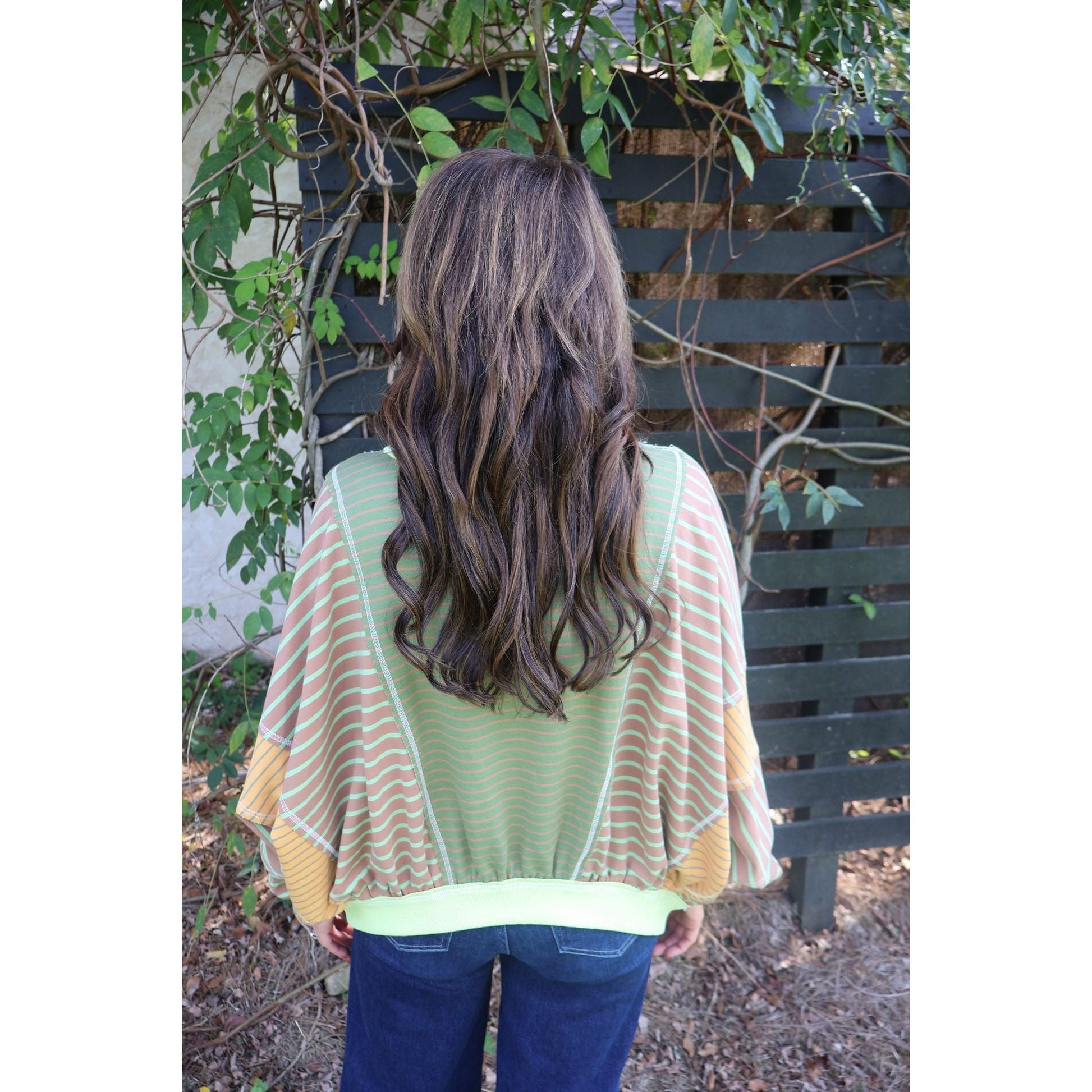 Annie Ks Boutique loose fit top featuring olive and latte mixed stripes, worn by a woman with long wavy brown hair.