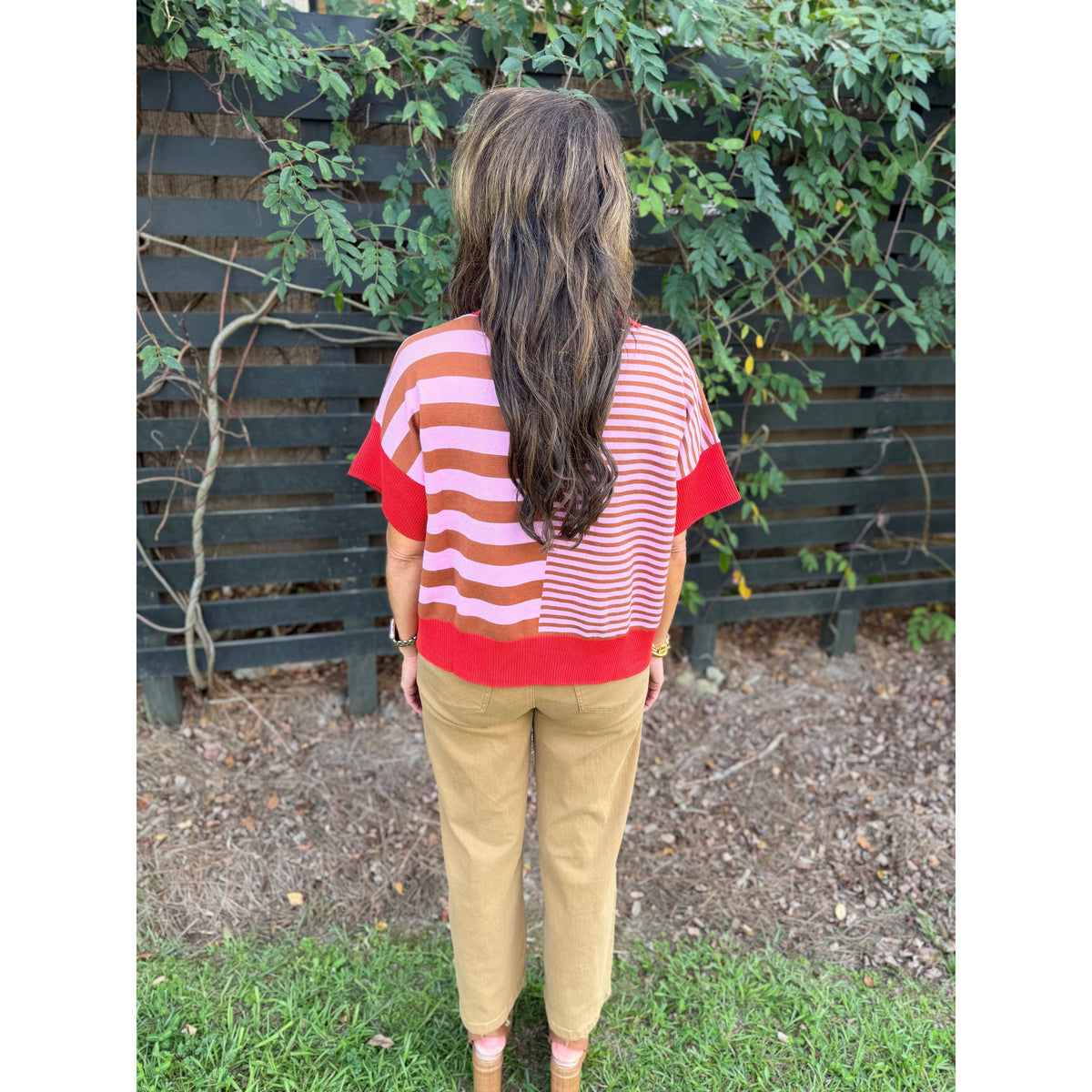 Annie Ks Boutique rust and caramel striped drop-shoulder sweater worn with tan trousers, back view
