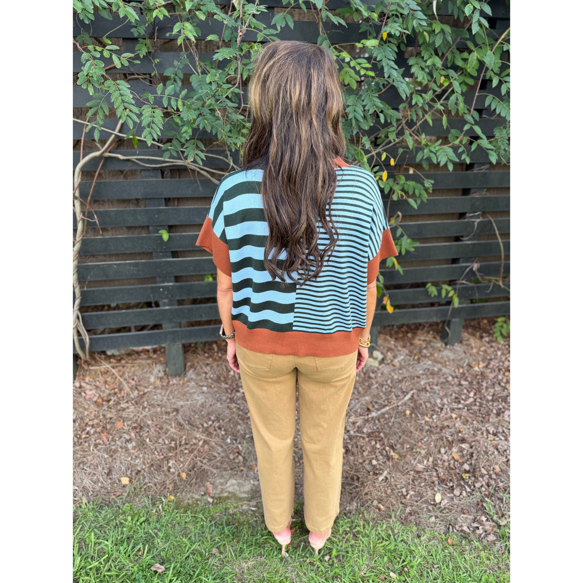 Annie Ks Boutique caramel and sea green striped drop-shoulder sweater worn with tan trousers, back view