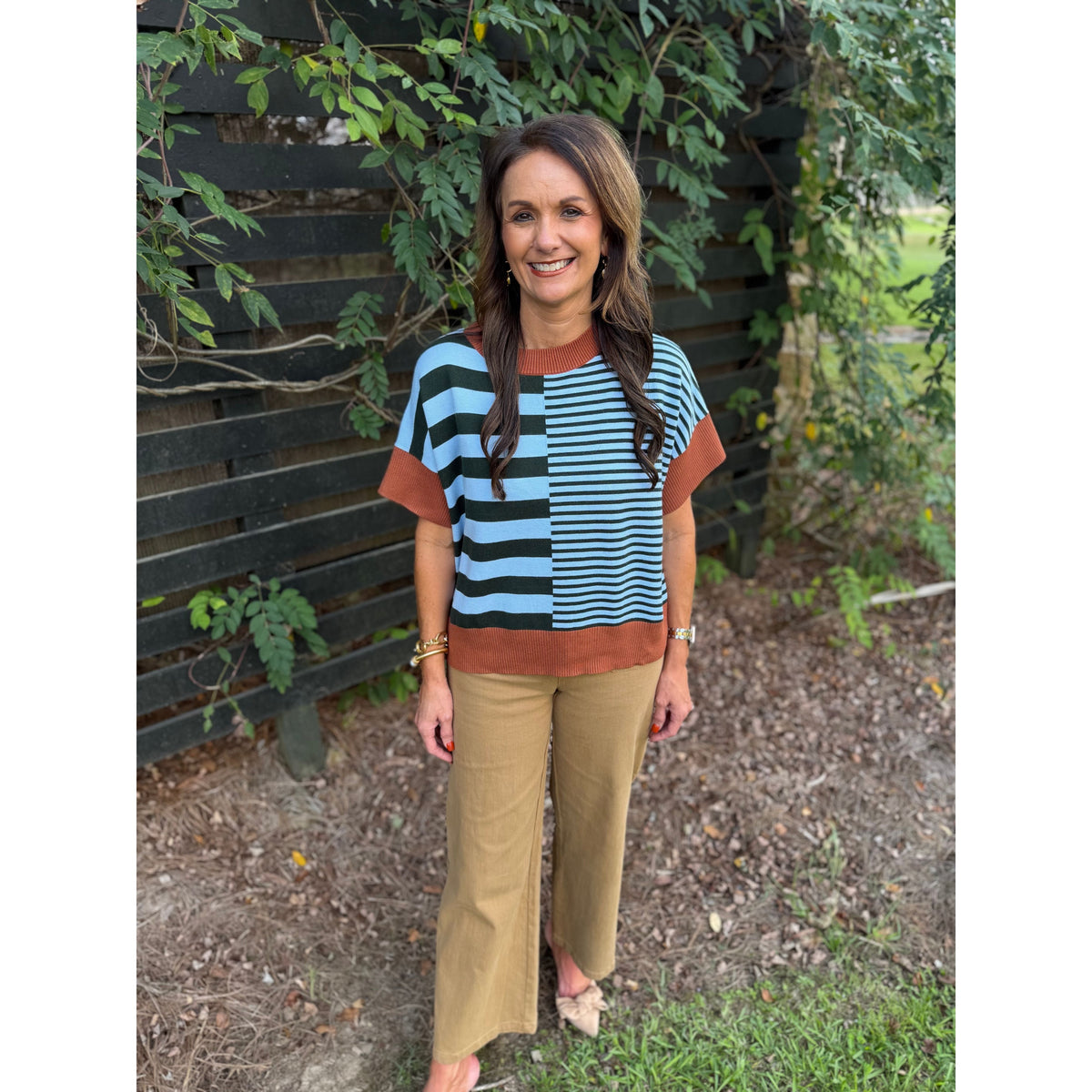 Annie Ks Boutique model wearing a caramel and sea green striped drop-shoulder sweater with wide-leg trousers.