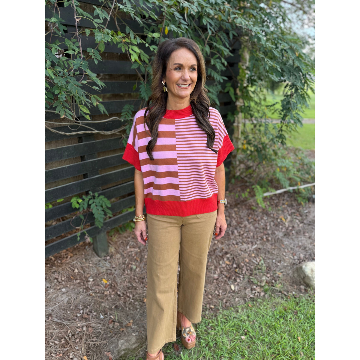 Annie Ks Boutique rust and caramel striped drop-shoulder sweater worn by a woman with tan trousers outdoors