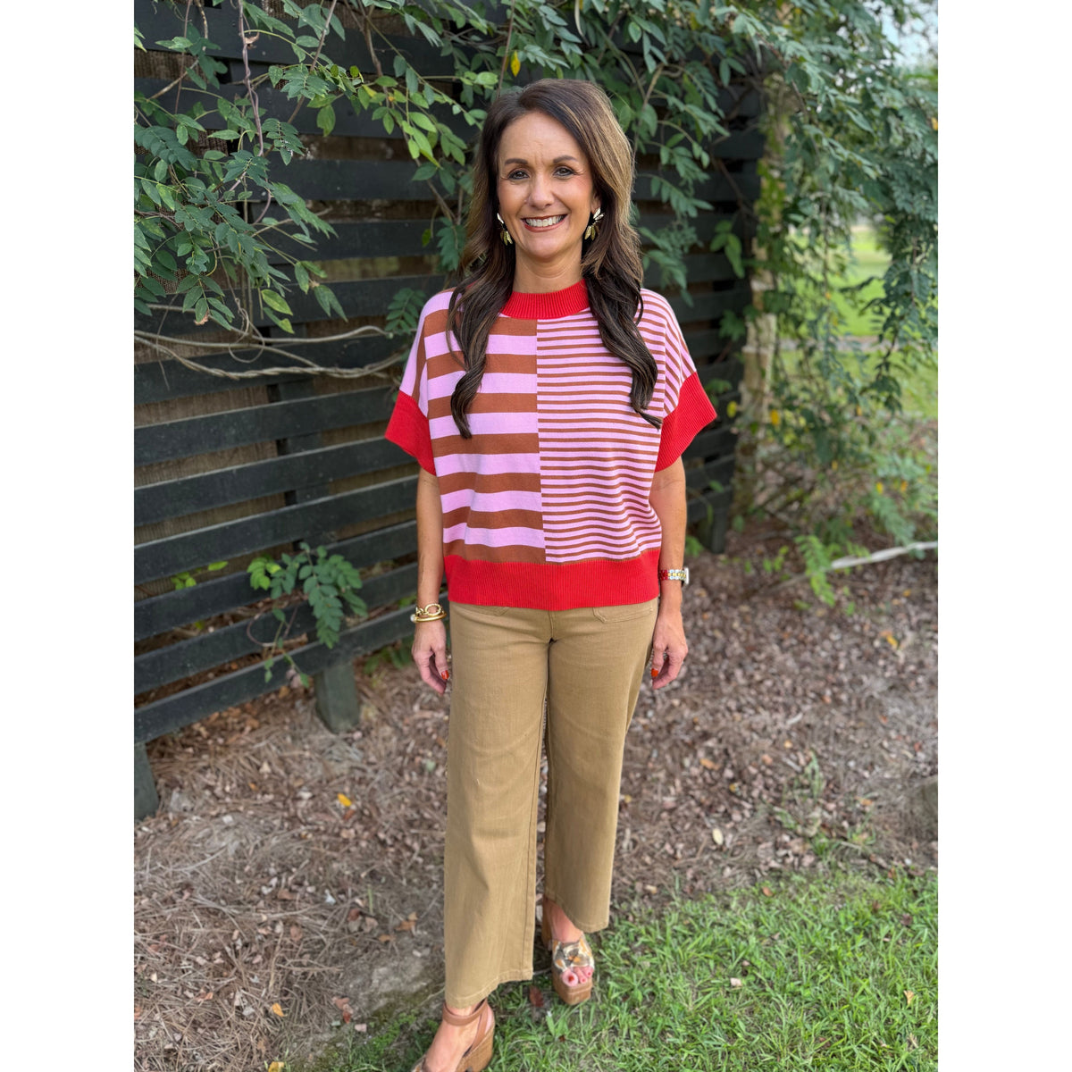 Annie Ks Boutique rust and caramel striped drop-shoulder sweater worn by a woman with tan trousers outdoors