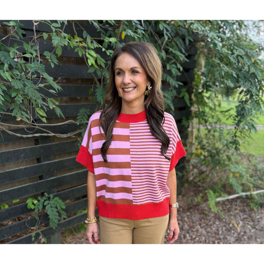 Annie Ks Boutique rust and caramel striped drop-shoulder sweater worn with tan trousers by a woman outdoors.