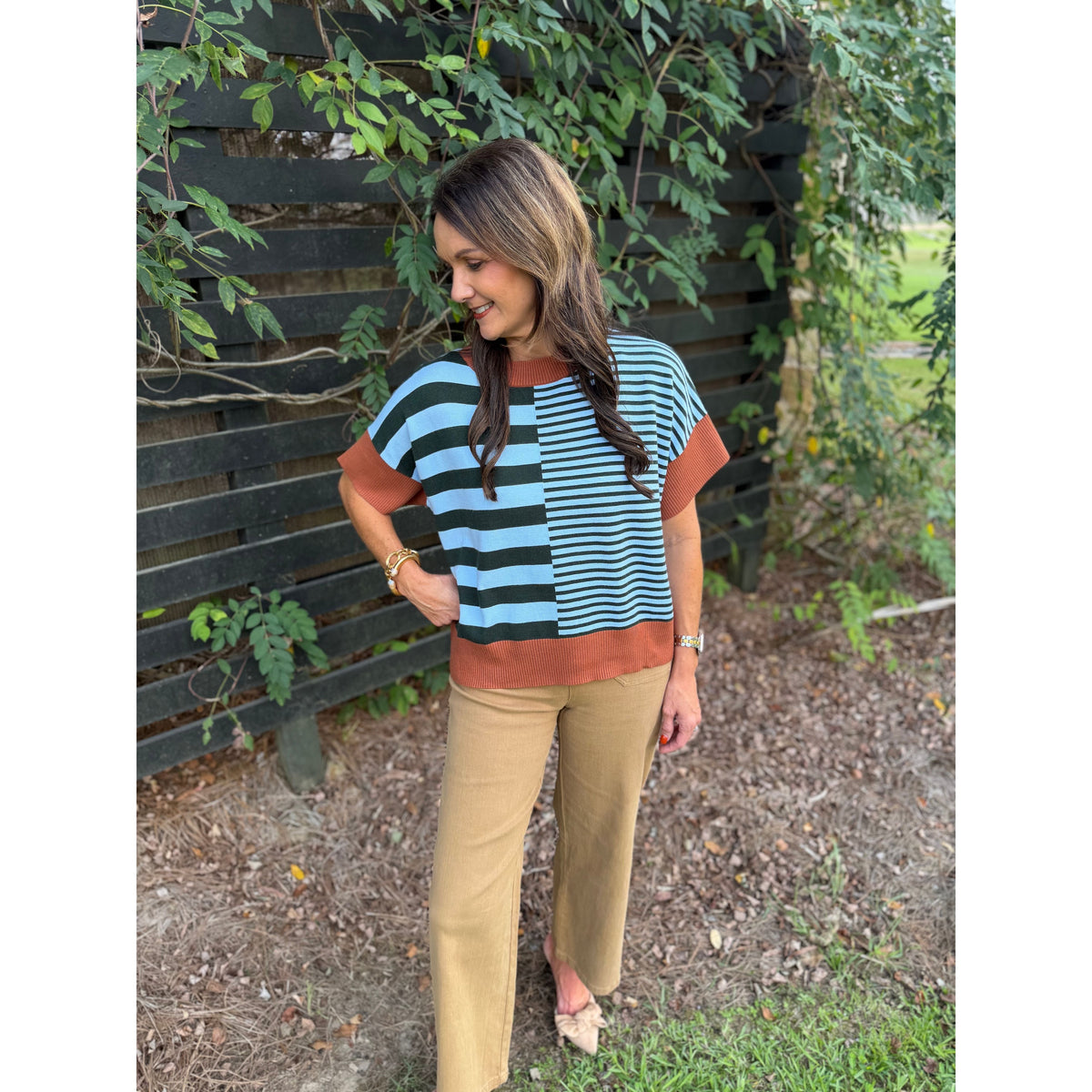 Annie Ks Boutique caramel and sea green striped drop-shoulder sweater worn with tan trousers outdoors