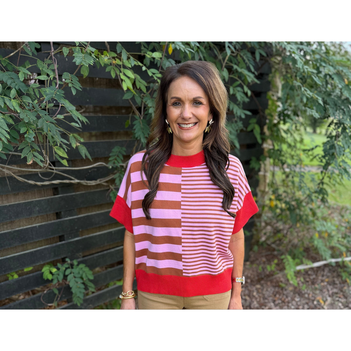 Annie Ks Boutique striped short-sleeve sweater in rust and caramel with a drop-shoulder fit worn with tan trousers.