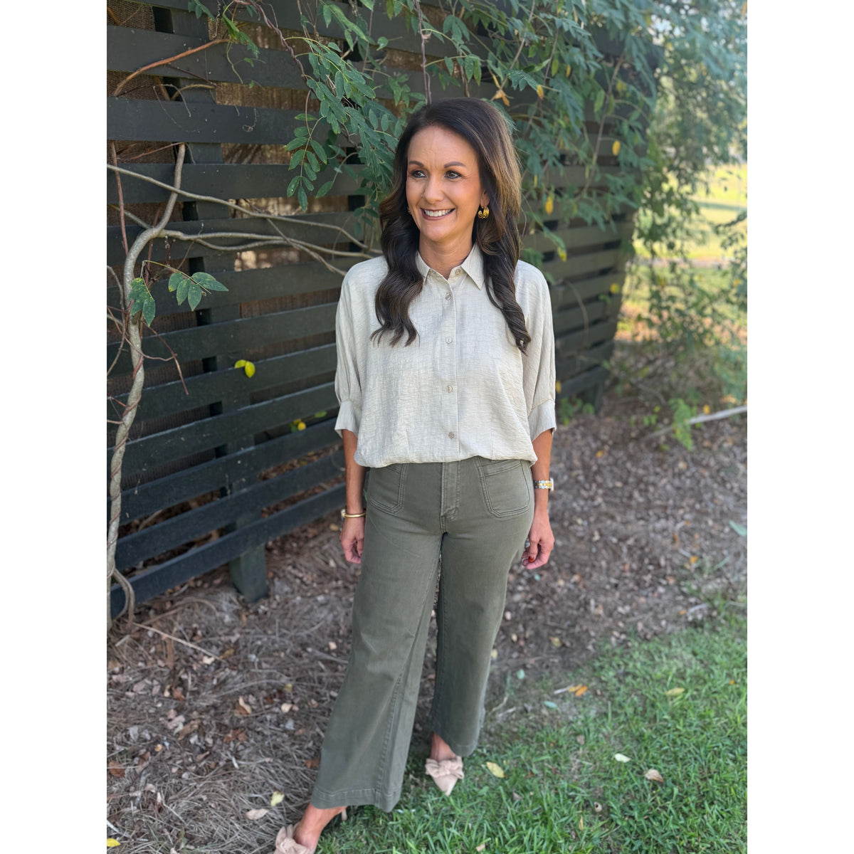 Annie Ks Boutique tan textured short sleeve blouse with a collar and button-front, worn with olive green trousers.