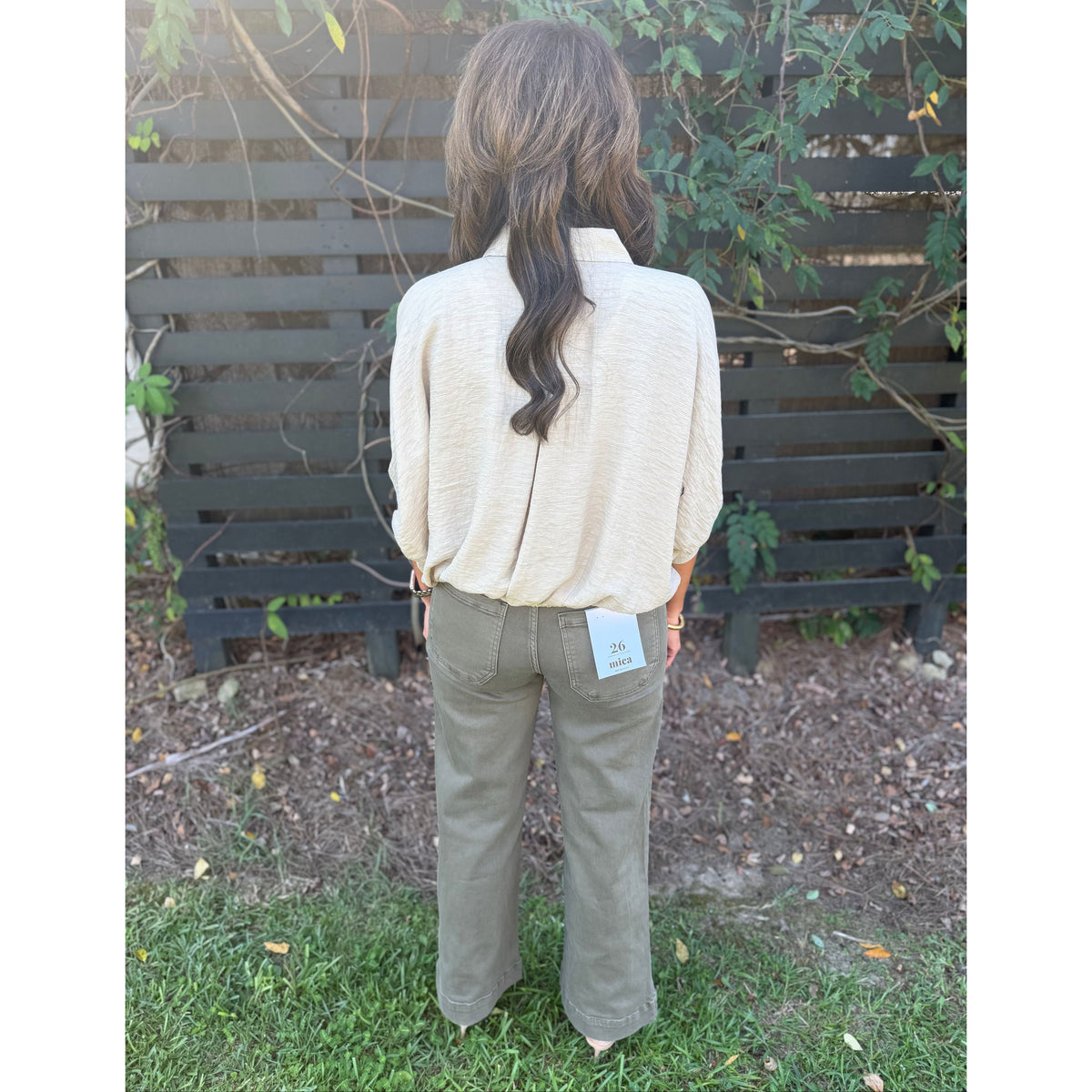 Annie Ks Boutique tan textured short sleeve blouse with a relaxed fit and dolman sleeves worn with olive trousers.