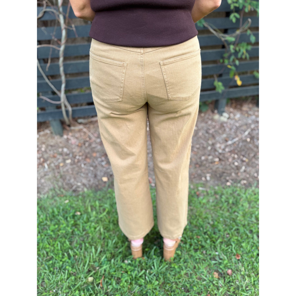 Annie Ks Boutique tan wide-leg trousers featuring back pockets, shown from behind on a model in a garden setting.