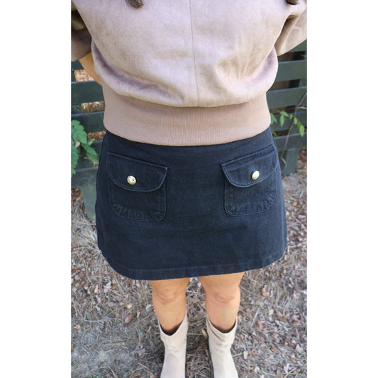 Annie Ks Boutique washed black woven skort featuring back pockets with gold buttons, worn with a tan top and boots.