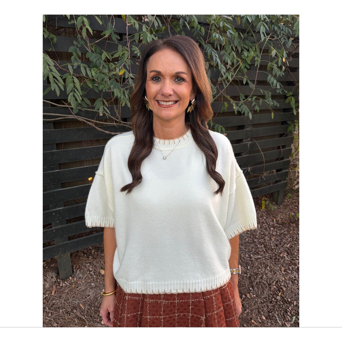 Annie Ks Boutique white mock neck sweater with contrast blanket stitching and short sleeves worn by a smiling woman.