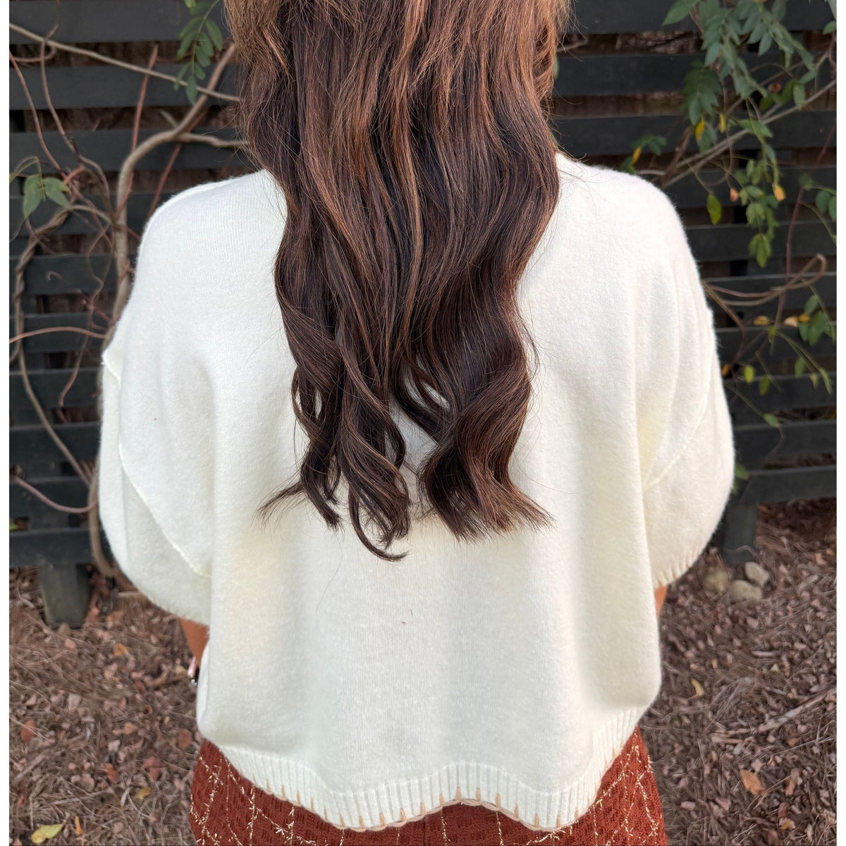 Back view of Annie Ks Boutique white mock neck sweater with wide sleeves and ribbed hem worn by a woman outdoors.