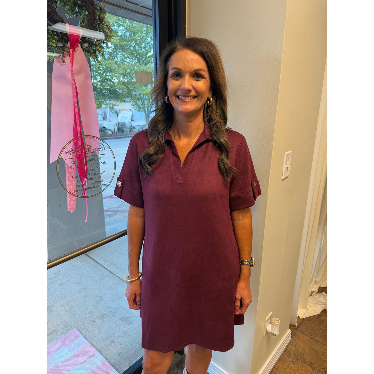 Annie Ks Boutique wine faux suede mini dress with a collared neckline and short sleeves worn by a smiling woman