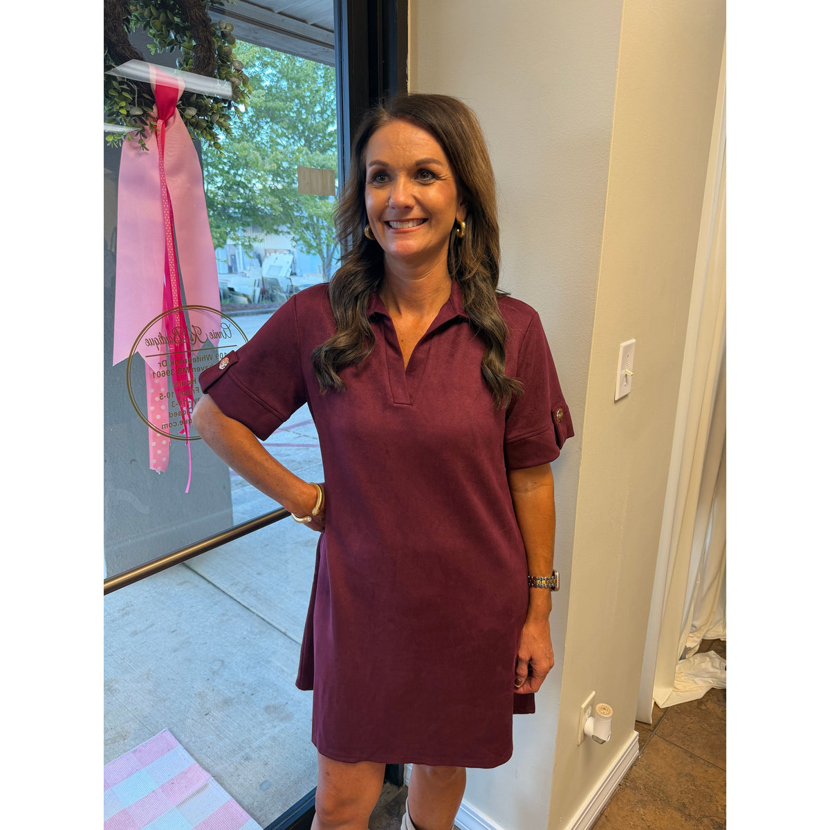 Annie Ks Boutique wine faux suede mini dress with a collared neckline and short sleeves worn by a smiling woman