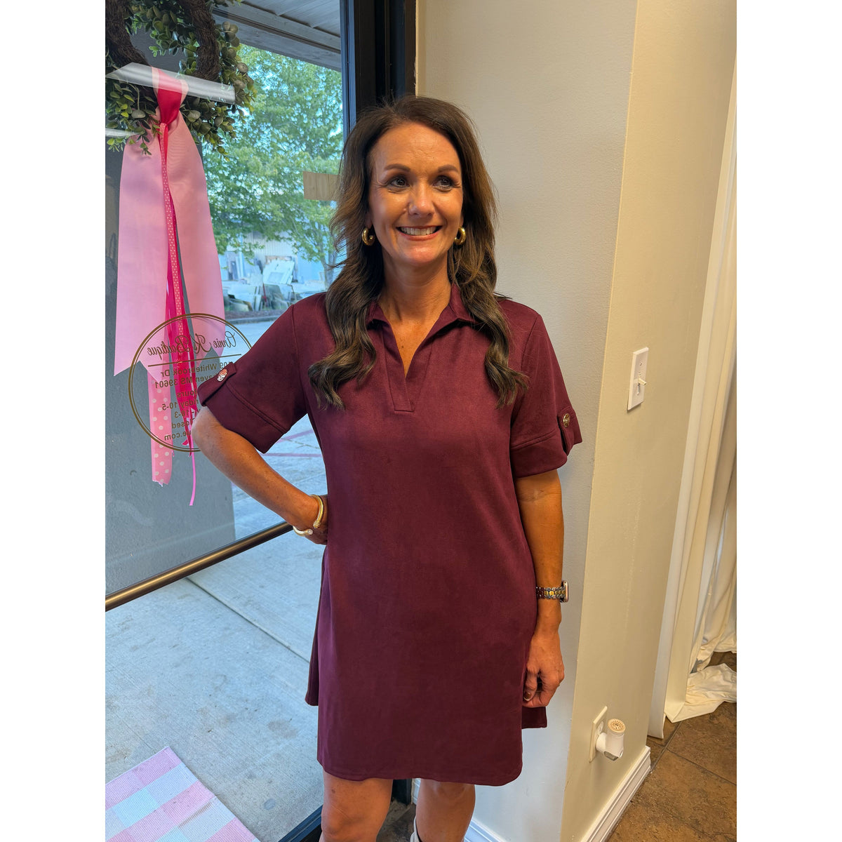 Annie Ks Boutique wine faux suede mini dress with a collared neckline and short sleeves worn by a smiling woman.