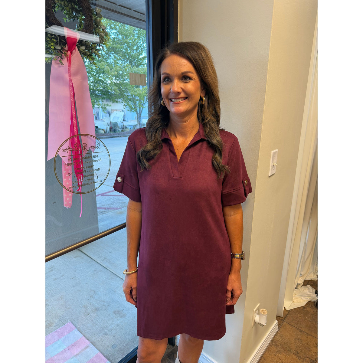 Annie Ks Boutique wine faux suede mini dress with a collared neckline and short sleeves on a smiling woman