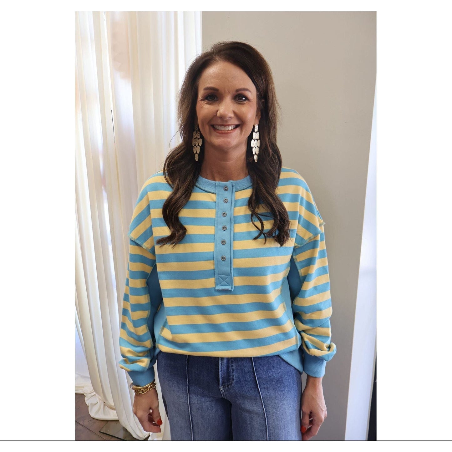 Annie Ks Boutique model wearing a yellow and blue striped oversized knit top with a half-button front and drop shoulders