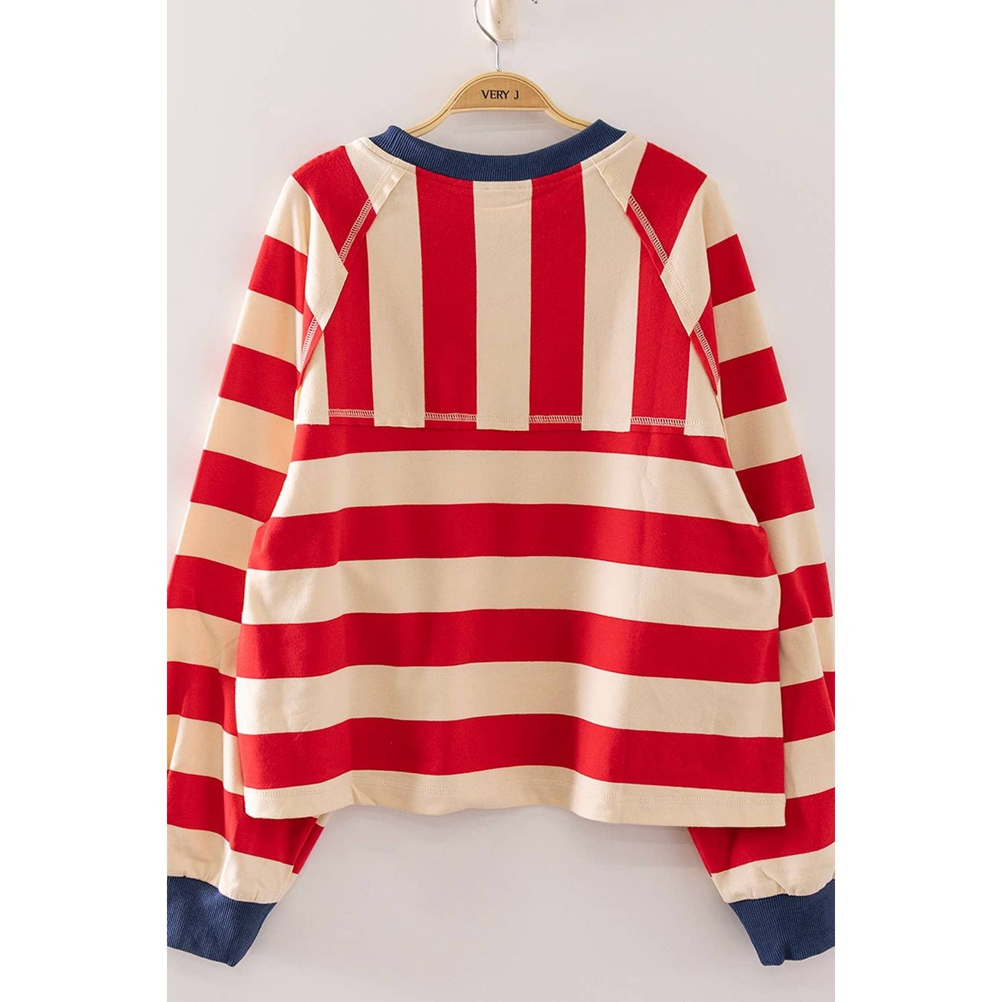 A red and cream striped long-sleeve raglan sweatshirt hanging on a wooden hanger with 'VIEW J' printed on it, set against a plain light background.